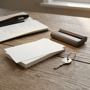 A stack of photo paper, an ink cassette, and a set of keys on a wood desk.