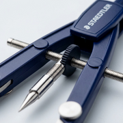 Macro photo focusing on the textured wheel and threaded spindle precision mechanics of a STAEDTLER compass.