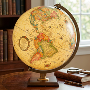 Lifestyle photo of the antique illuminated Carlyle desk globe glowing on a wooden library table, showing North America.