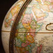 Extreme close-up macro photograph focusing on the detailed print surface of the Replogle Hastings Globe against the textured metal meridian, showing precise cartography and clean text.