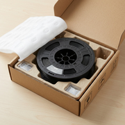 A close-up photograph of the 3PI Tech Solutions nylon filament spool, which features a intricate web-like plastic structure, resting inside a form-fitting padded insert within a sturdy unboxing tray, demonstrating protective delivery.