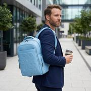 A person with the PU Drift Blue Bugatti Rick Ross backpack walking on a paved pathway during the day.