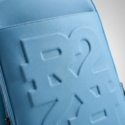 Macro detail of the debossed RR logo texture on the blue leather Bugatti backpack.